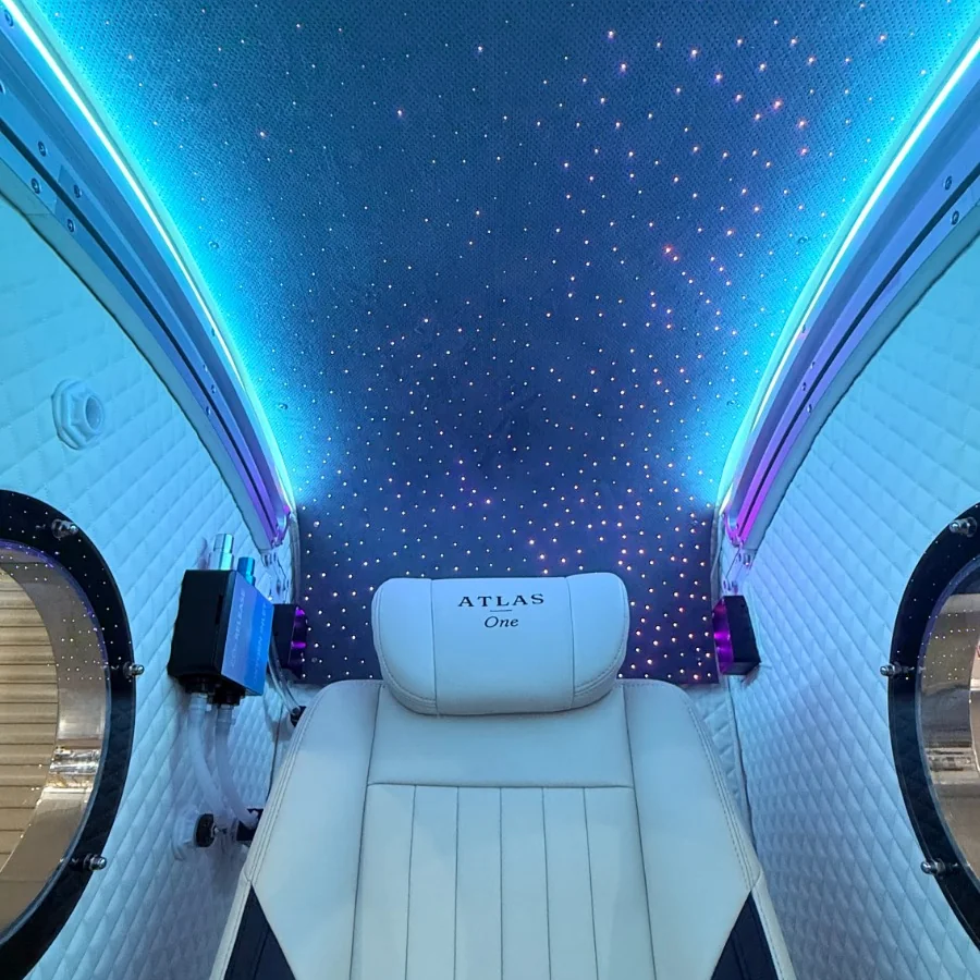 Atlas One cabin interior lit blue, starlight ceiling above the leather seat